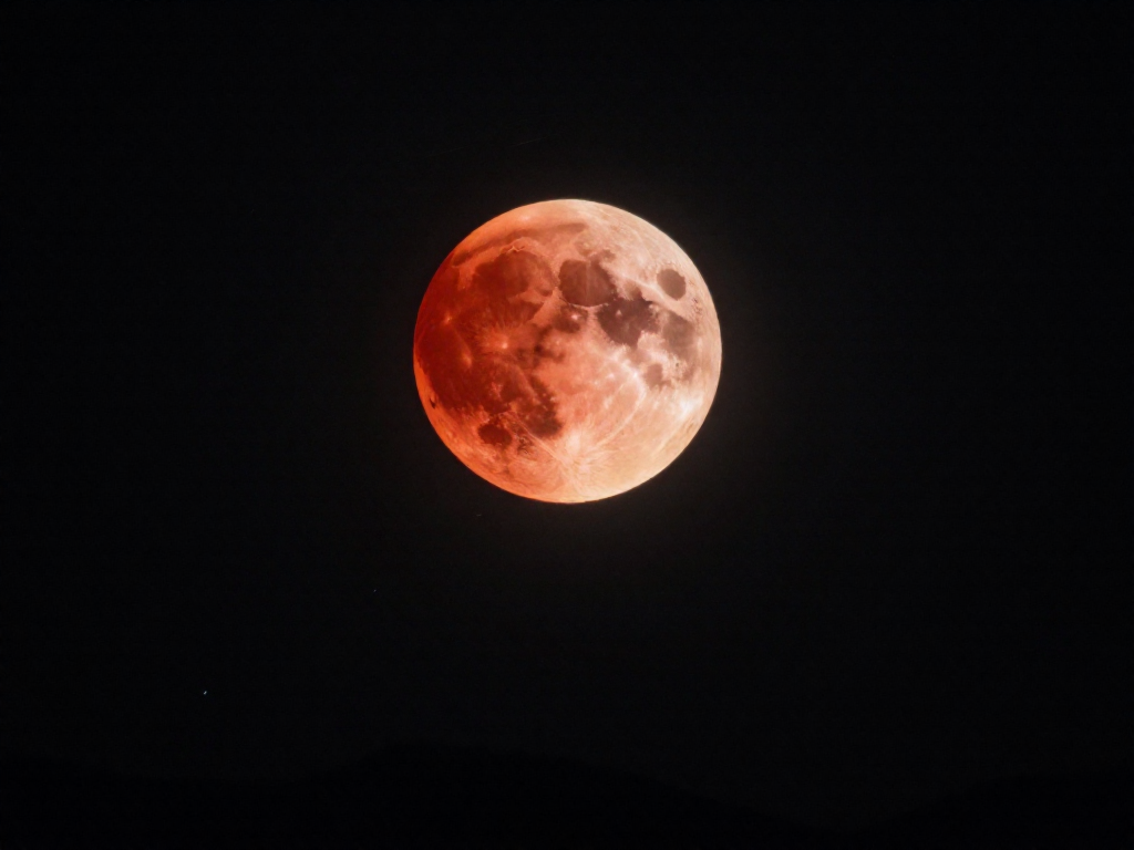 A deep red blood moon glowing during a total lunar eclipse in a starry night sky